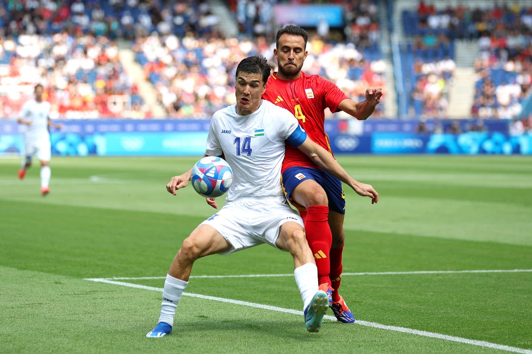 PARIS, FRANCE - JULY 24: Eldor Shomurodov #14 of Team Uzbekistan is challenged by Eric Garcia #4 of Team Spain during the Men's group C match between Uzbekistan and Spain during the Olympic Games Paris 2024 at Parc des Princes on July 24, 2024 in Paris, France.